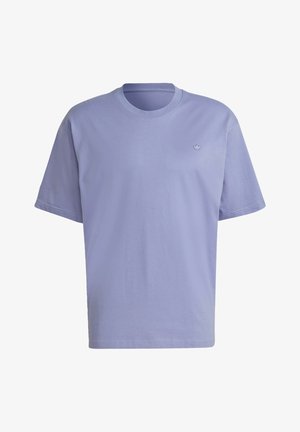 Personne portant un t-shirt violet, un jean bleu retroussé, des chaussettes blanches et des baskets blanches à rayures noires, debout les bras levés.