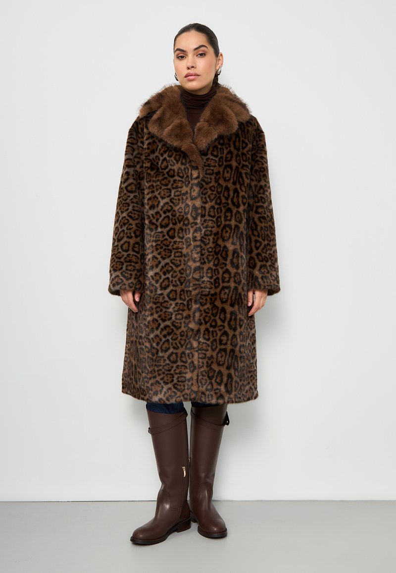 Cappotto di pelliccia leopardato con colletto di pelliccia marrone, con maniche lunghe, taglio dritto e lunghezza media. Abbinato a stivali alti marroni.