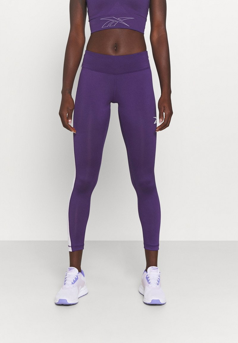 Lila idrottsleggings med hög midja och kontrasterande sidopaneler. Matchas med en passande kort toppen och vita löparskor.