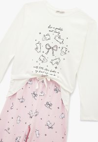 Weißes Langarmoberteil mit schwarzem Hasen- und Sterndruck, das ein Schleifenmotiv zeigt. Rosa Hose mit ähnlichem Hasen- und Schleifenmuster, elastischem Bund.