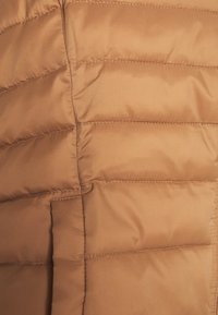 Braune Daunenjacke. Merkmale ein gestepptes Muster mit horizontalen Nähten, einer weichen Textur und einem glatten, glänzenden Stofffinish.