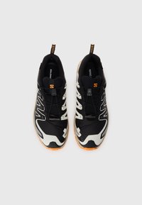 Black athletic shoes with white and orange accents, featuring a mesh upper, lace system, and a textured rubber sole for traction.