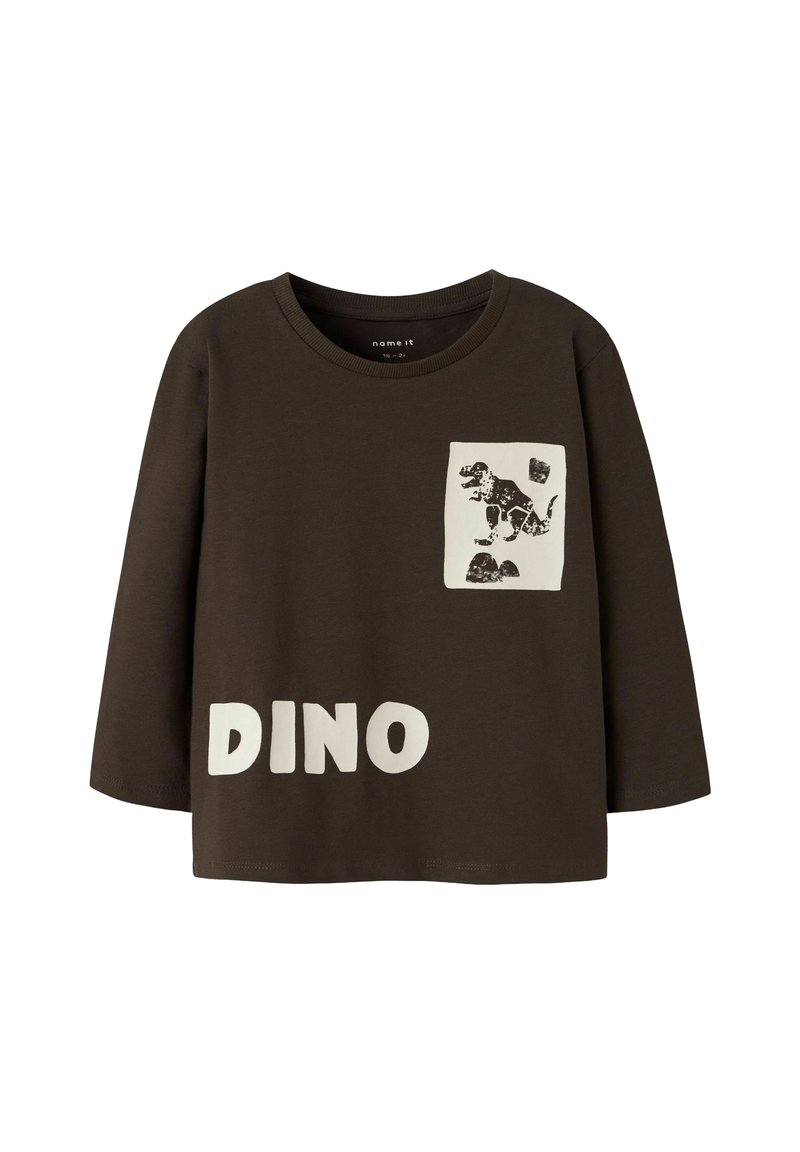 Rjava srajca z dolgimi rokavi z belim napisom "DINO" in grafiko dinozavra na sprednjem žepu. Narejena iz mehke tkanine s sproščenim krojem.