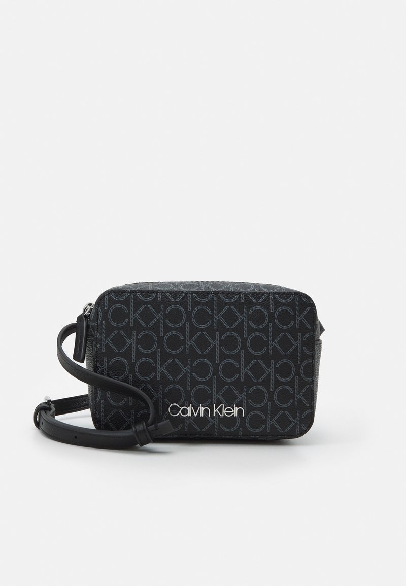 Borsa a tracolla nera di marca con motivo logo testurizzato, dotata di chiusura con zip e tracolla regolabile. Marchio "Calvin Klein" bianco.