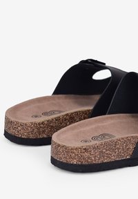Schwarze Slipper-Sandalen mit Korkfußbett, strukturiertem braunem Innenleben und kontrastierender glatter schwarzer Außensohle. Verfügt über eine abgerundete Zehenform und ein Ausschnittdesign.