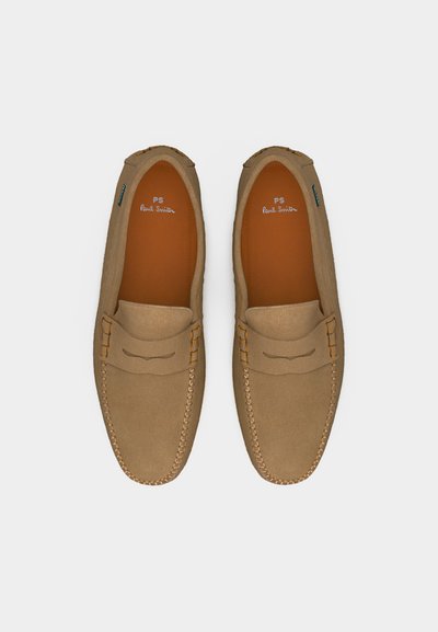 Mocassins en daim beige avec coutures mocassins et détail de bride, vus de dessus sur un fond blanc.