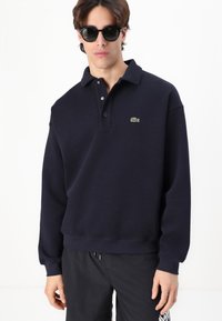 Sudadera polo azul marino hecha de una mezcla de algodón, con un cuello clásico, tapa de tres botones y logo bordado en el pecho.