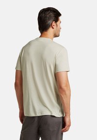 Light green short-sleeve T-shirt with a smooth texture. Features a crew neck and is paired with dark gray shorts. Slightly relaxed fit.