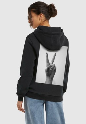 Schwarzer Hoodie mit einem weißen Grafikmotiv einer Hand, die ein Friedenszeichen macht. Die Kapuze ist verstellbar; der Stoff wirkt weich und gleichzeitig strapazierfähig.