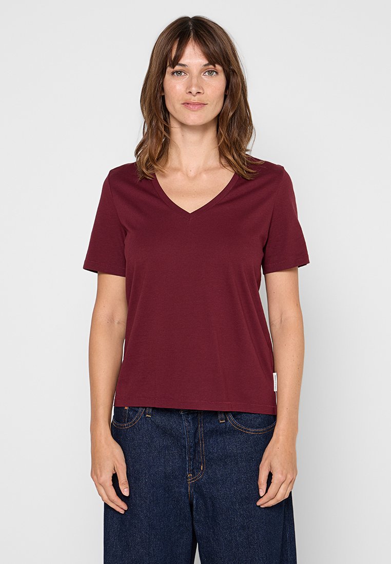 Bordowy t-shirt z dekoltem w serek i krótkimi rękawami, wykonany z miękkiej bawełny, o luźnym kroju, z małą metką na dolnej stronie.