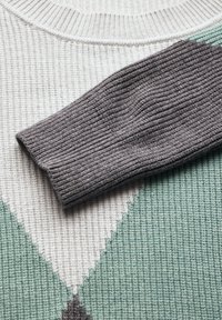 Ulltröja med geometrisk design i dämpade färger: kräm, mintgrön och kolgrå. Ribbad textur på ärmen.