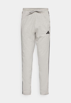 Pantalones de chándal gris claro hechos de material suave, con franjas laterales negras y una cinturilla elástica con cordón. Incluye el logo de Adidas.