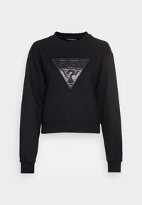 Sudadera corta negra hecha de tejido, con un parche triangular texturizado que lleva un logo en el centro. Mangas largas con puños acanalados.