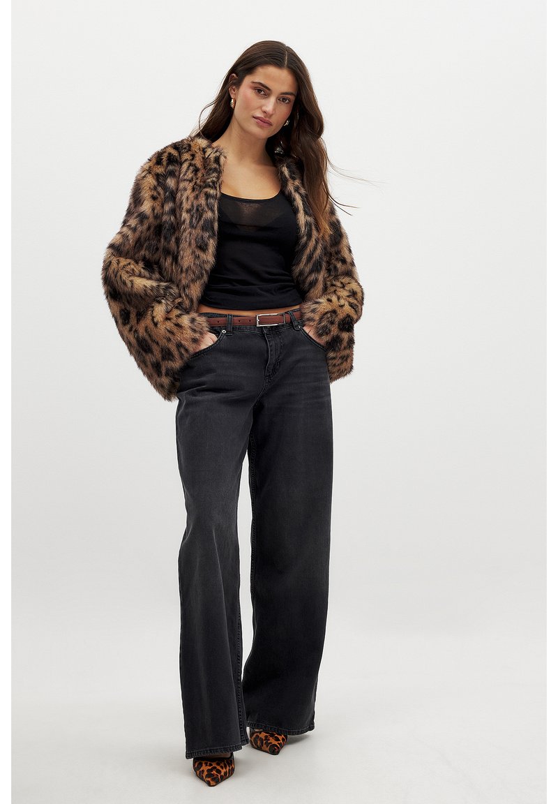 Faux fur leopard print jacket with loose fit, paired with black high-waisted jeans and animal print heels. Simple black top underneath.
