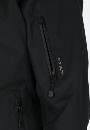 Black waterproof jacket with adjustable zippered pockets, smooth texture, and "STX 20.000" lettering near the pocket.