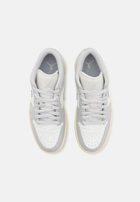 Sneakers med en vit lädertåbox, ljusgrå lädersidor och grå mesh-tunga. Runda skosnören och strukturerad gummisula.