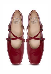 Pair of glossy dark red leather Mary Jane flats with square toes and double adjustable straps, labeled Cesare Gaspari Barcelona.