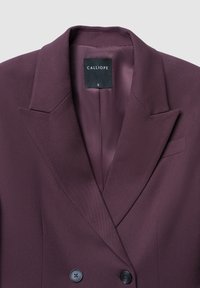Blazer bordeaux doppiopetto con una texture liscia, revers affilati e due bottoni neri. L'interno presenta un rivestimento simile alla seta.