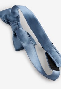Blaue Satin-Haarband mit einer Schleife. Verfügt über ein flaches Design und eine strukturierte Oberfläche. Verstellbarer Riemen mit einem Klettverschluss.