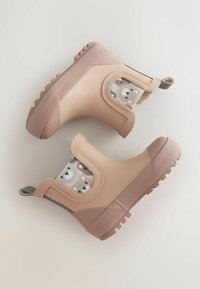 Cizme roz din cauciuc pentru gleznă, cu un finisaj neted, părți laterale texturate și o căptușeală cu model jucăuș. Talpă cu caneluri pentru aderență.