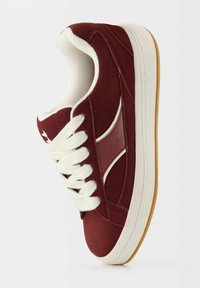 Baskets en daim bordeaux avec lacets blancs, col rembourré et accents subtils en cuir. Dotées d'une semelle en caoutchouc et de bandes latérales contrastantes.