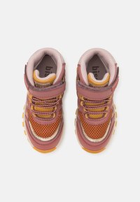 Chaussures de sport arborant un mélange de rose foncé, de mesh orange et d'accents métalliques. Comprend une sangle Velcro et une semelle en caoutchouc texturée.