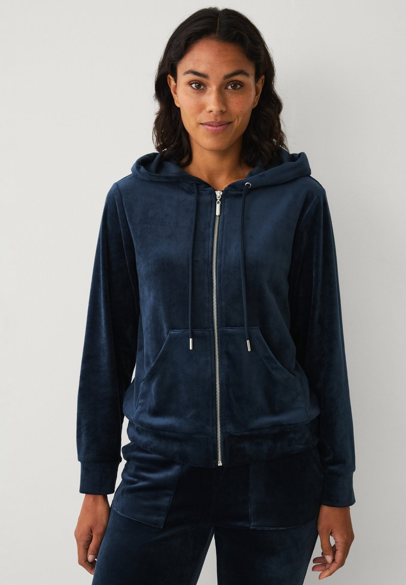 Sudadera con cremallera de felpa en color azul marino, con capucha ajustable, bolsillos frontales y puños de canalé, que presenta una textura suave y lisa.
