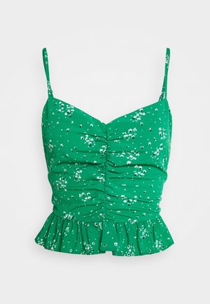 Crop top vert à fines bretelles avec imprimé floral blanc, devant froncé et ourlet à volants.