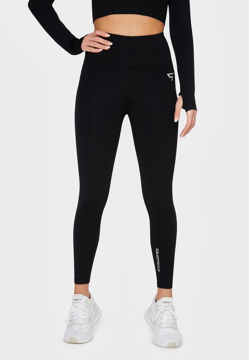Black leggings made from stretchy fabric with a high waist. Features include a logo on the lower leg and a smooth, fitted design.