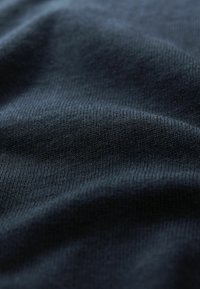 Navy blue knit fabric with a soft texture, featuring a ribbed pattern and slight stretch, showing fine details of the weave.