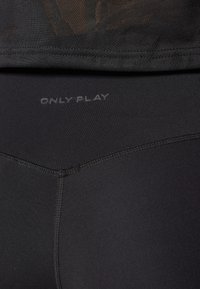 Fekete leggings sima felülettel, rajta szürke "ONLY PLAY" logóval. A dizájn testre szabott varrásokat és rugalmas derékpántot tartalmaz.