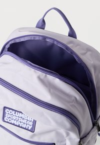 Σακίδιο πλάτης της Columbia Sportswear Company σε λεβάντα με ανοιχτό κύριο διαμέρισμα και φερμουάρ στην μπροστινή τσέπη σε λευκό φόντο.