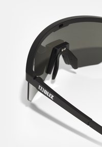 Mustad mustasportlikud prillid, millel on kumer disain ja tumedad toonitud läätsed. Omab metallaktsente ja logo käe peal.