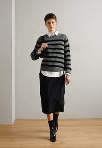 Pulover din lână cu dungi gri, cămașă albă cu guler, fustă midi neagră și botine negre. Textură netedă, croi lejer, design minimalist.