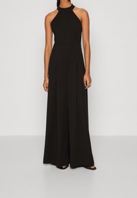 Jumpsuit negro con cuello halter, que presenta un busto ajustado, diseño de pierna ancha y pliegues. Fabricado con una tela suave y con un corte clásico de largo completo.