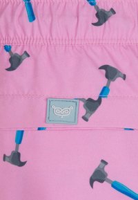 Roze stof met een herhalend hamerpatroon in grijs en blauw, met gathered taille-detail en een lichtblauwe merklabel.