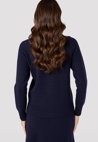 Maglione navy con maniche lunghe, polsini e orlo a coste. Tessuto a maglia liscio, design semplice, che offre un aspetto pulito e aderente dal retro.