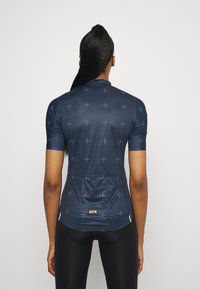 Námořnicky modrý cyklistický dres s krátkými rukávy, zdobený mřížkovým vzorem a zadní kapsou. Vyrobený z hladké, lehké látky s logem.