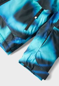 Veste imperméable avec un design dégradé bleu et noir, dotée d'une poche zippée, d'une texture lisse et d'une construction en tissu durable.