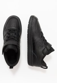 Svarta idrottsskor med en slät läderövre del, perforerad tå för andningsförmåga, vadderad krage och texturerad gummisula.