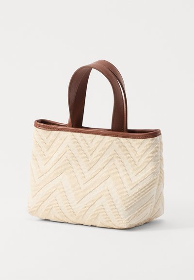 Sac tissé beige avec un motif en chevrons, doté de poignées et de bordures en cuir marron, de forme rectangulaire et d'une surface texturée.
