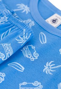 T-shirt en coton bleu clair avec des motifs imprimés blancs de voitures, de planches de surf et de palmiers. Encolure arrondie et poignets élastiqués.