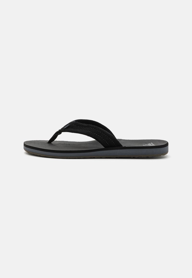 Tongs noires avec une semelle en caoutchouc texturé, équipées de deux sangles en tissu et d'un matelas de pied légèrement rembourré. Design simple, sans motifs visibles.