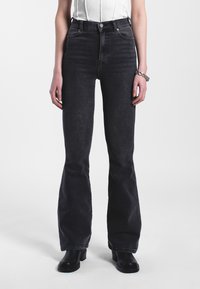 Korkeavyötäröiset mustat leveälahkeiset farkut, jotka on valmistettu denimmateriaalista. Niissä on klassinen viisi-taskuinen muotoilu ja hienovaraiset tikkausjatkumoita.