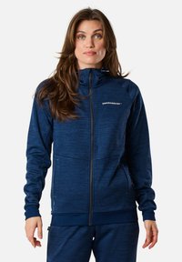 Navyblaue Zip-Jacke aus strukturiertem Stoff. Mit hohem Kragen, Fronttaschen und dem Logo "SWEDEMOUNT" auf der Brust.