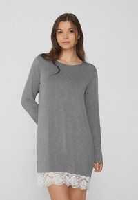 Vestido gris de manga larga con escote redondo y borde de encaje blanco en el dobladillo. Tejido suave con un corte holgado, que llega a medio muslo.