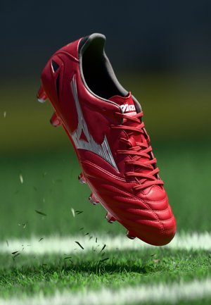 Crampons de football rouges avec une finition brillante, présentant un design d'accent blanc, six taquets sur la semelle et un côté texturé pour l'adhérence.