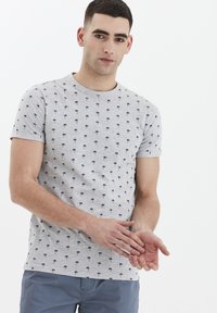 Grå bomulds t-shirt med korte ærmer, prydet med et gentaget sort palmetræsmønster. Enkel rund halsudskæring, let figursyet design.