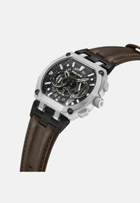 Svart och silver kronograf klocka med ett texturerat brunt läderarmband. Oktagonalt hölje i rostfritt stål, två tidsindikatorer och kontrasterande accenter.