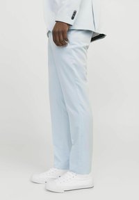 Pantalones ajustados de color azul claro, combinados con zapatillas blancas. Los pantalones cuentan con una tela suave y costuras alineadas.